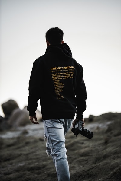 Wearing a black hoodie and a white denim jeans, SLR cameras, holding a black man
